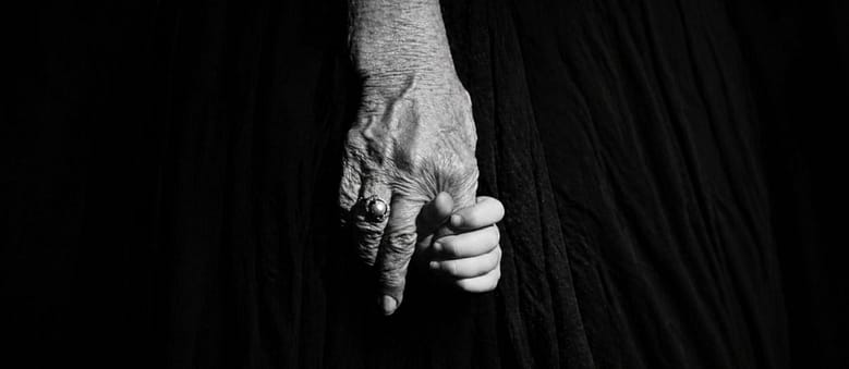 Black and white photograph of a young child holding an elderly woman's hand, circa 1970