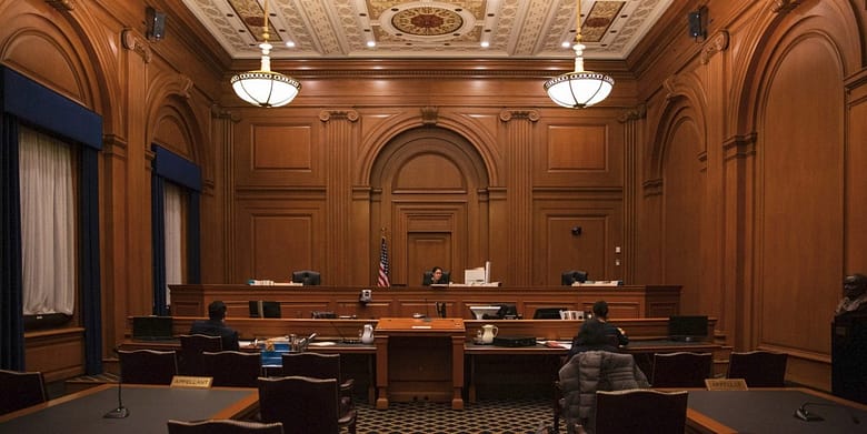 Nearly empty courtroom with unoccupied appellant and appellee tables facing the judge's bench