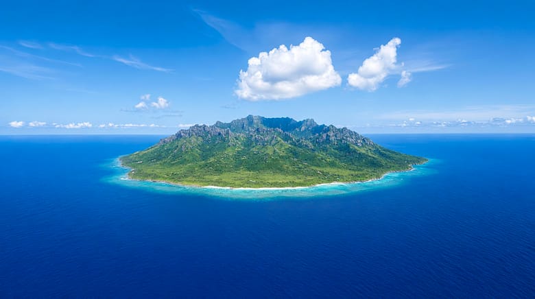 An aerial view of one island in open ocean with no other land in sight, the nearest shore far beyond the horizon.