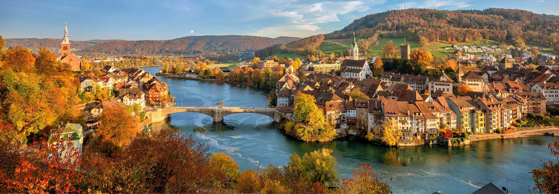 European river winding through a historic town in autumn, illustrating the type of destination environment that makes river cruising attractive to premium travelers.