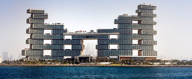 Luxury waterfront hotel with stacked modern towers rising above the shoreline and open sea in the foreground.