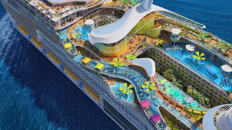 Aerial view of a modern cruise ship deck with multiple pools, water features, sun loungers, and outdoor leisure spaces at sea.