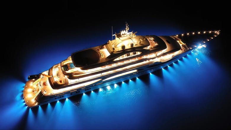 Aerial night view of a luxury cruise ship illuminated against dark water, illustrating the repositioning problem in luxury cruise demand architecture.