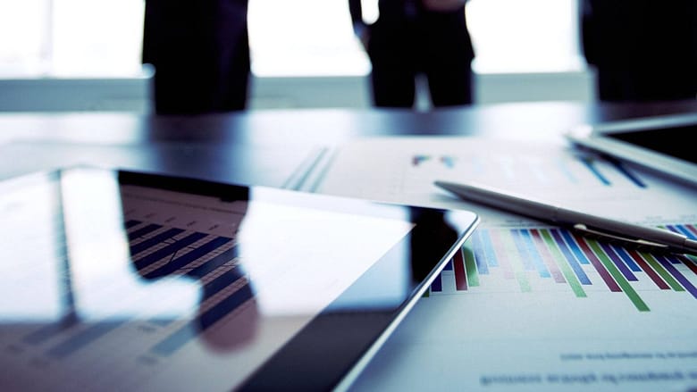 Blurred strategy meeting with charts and tablet, representing hotel demand and distribution analysis.