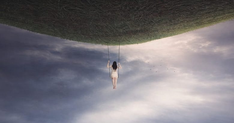 Woman on a swing suspended from an inverted grassy landscape above storm clouds, illustrating the structural paradox facing independent luxury hotels in a growing market