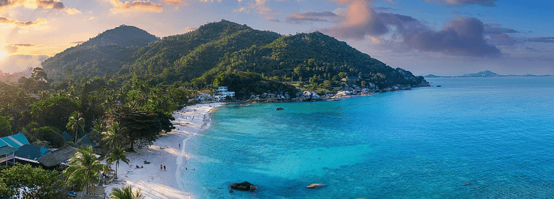 Panoramic view of a luxury resort set between mountains and the ocean at sunrise